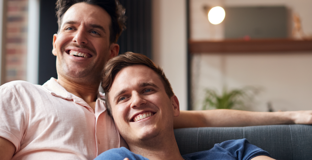 male couple laying on couch smiling
