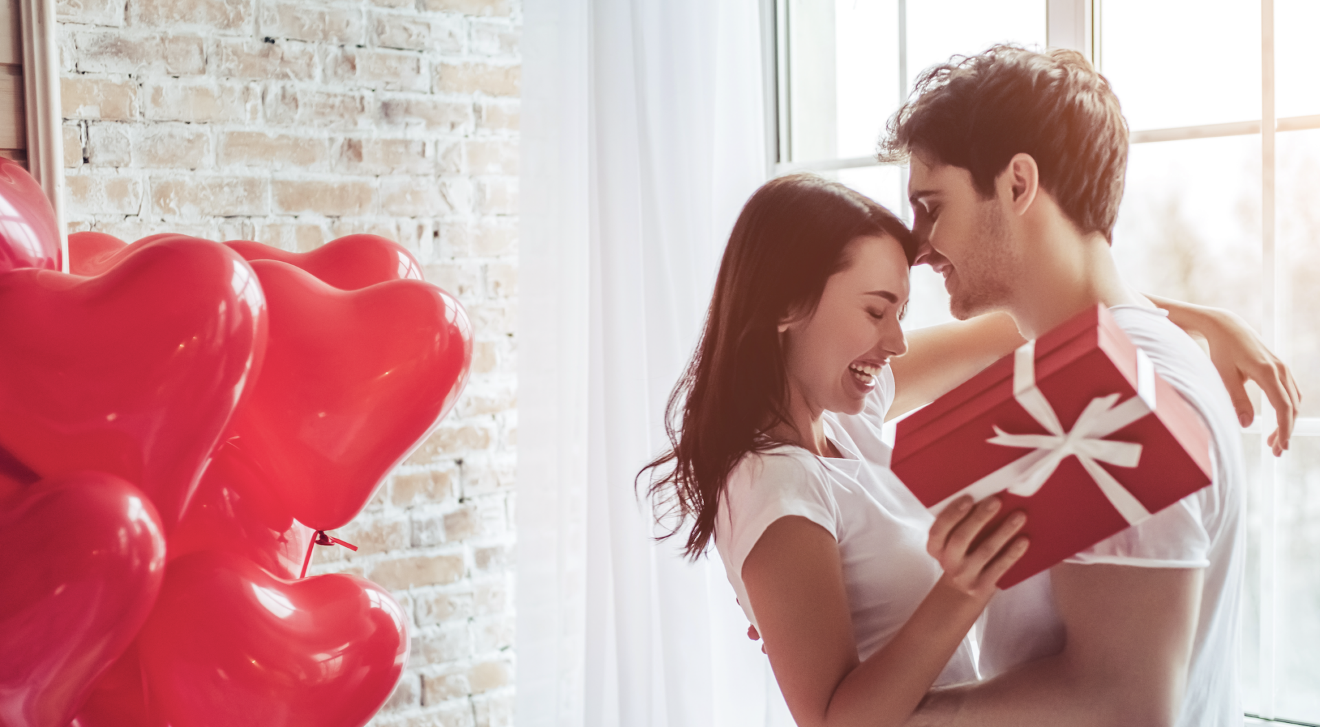 new open relationship feature image. Girl and guy embrace holding red gift, by red balloons.