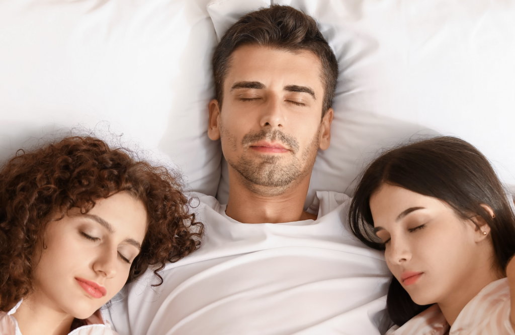 man in bed with two women